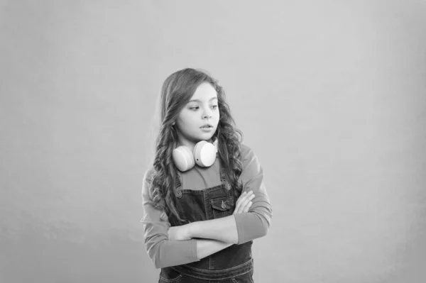 Χίπστερ παιδί. Ένας μικρός χίππις κρατάει τα χέρια του σε μπλε φόντο. Αξιολάτρευτο χίπστερ με μακριά σγουρά μαλλιά φορώντας σύγχρονα ακουστικά. Χαριτωμένο μικρό παιδί σε μοντέρνο χίπικο στυλ — Φωτογραφία Αρχείου