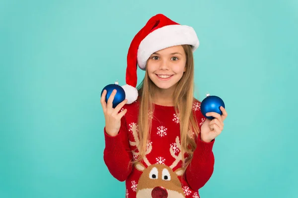 Een kerstboom versieren. Meisje glimlachende gezicht houden ballen ornamenten blauwe achtergrond. Laat het kind kerstboom versieren. Favoriete deel versieren. Voeg meer decoraties toe. Kinderen betrekken bij het versieren — Stockfoto
