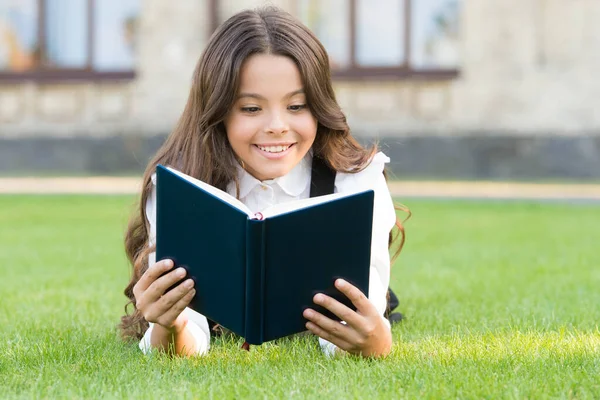 Wie heeft rust nodig als er nog een boek gelezen moet worden. Schattig klein kind lees boek over groen gras. Schattig klein meisje ontspannen lezen boek buiten. Grijp elke dag met een nieuw boek. School en kennis — Stockfoto