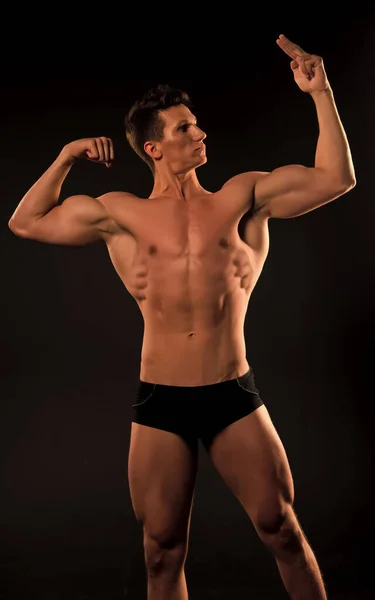 Uomo muscoloso. uomo muscoloso con addominali. muscolare punto bodybuilder uomo sul suo muscolo. bicipiti e tricipiti dell'atleta muscoloso. mantenendo il suo corpo in buona forma . — Foto Stock