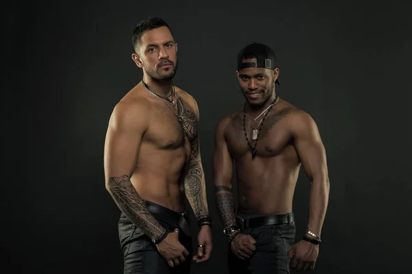 Sport with fitness and bodycare. Men with fit tattooed bodies. African and hispanic men with sexy bare torsos. Fashion models with tattoo in jeans. Sportsmen with muscular chest and belly — Stock Photo, Image