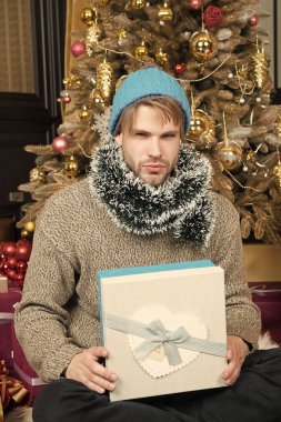 Şapkalı ciddi yüzle maço, kazak tutun mevcut sarılmış