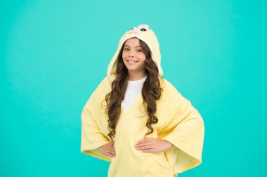 Hafta sonu tatili. Uzun saçlı çocuk pelüş pijama giyiyor. Çok güzel pijamalar. Kapüşonlu pijama giyen küçük bir kız. Rahat ve rahat hissediyorum. Çocuk modası. Ev kıyafetleri. Mutlu çocukluk