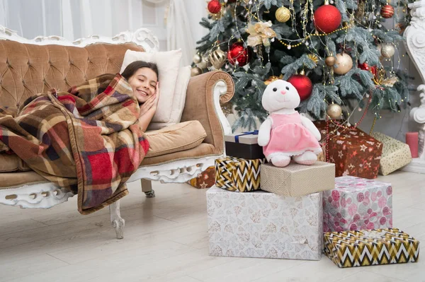 Magical moment. Christmas night. Happy new year. Family holiday. Christmas tree and presents. Dreaming about gifts. Little girl sleep couch near christmas tree classic interior. Believe in miracles