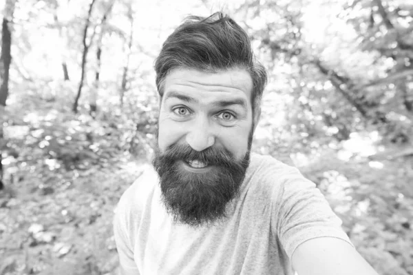 La barbe peut rendre un homme plus brutal. Homme heureux avec moustache longue et poils de barbe en plein air. Homme brutal souriant avec visage non rasé et coiffure élégante. Homme barbu dans un style décontracté sur un paysage naturel — Photo