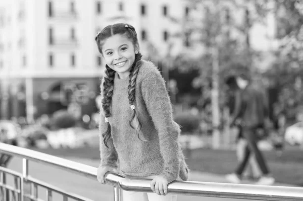 Pequeño guapo. Adorable niño pequeño con una sonrisa encantadora en el día de verano. Niño pequeño con el pelo moreno sonriendo en el estilo de moda casual. Niña feliz con aspecto de belleza en el fondo urbano — Foto de Stock