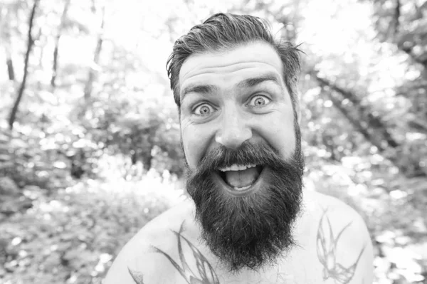 Summer madness. Man cheerful bearded hipster taking selfie in wild nature. Guy crazy emotional face surviving in hot forest. Summer vacation concept. Having fun. Blogger summer natural environment
