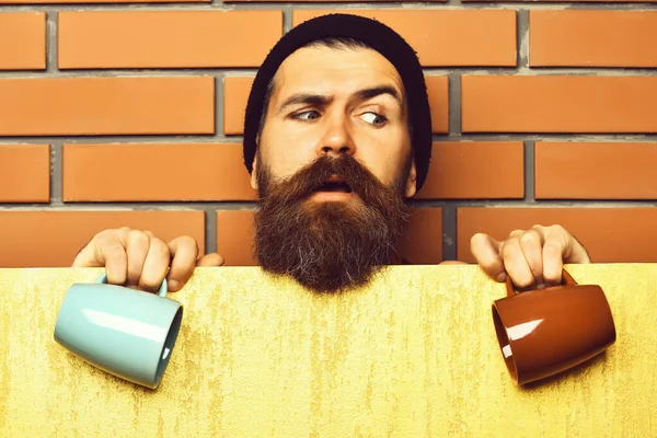 Barbudo brutal hipster caucásico con hoja de papel y tazas —  Fotos de Stock