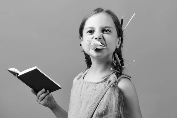 Menina mastiga pedaço de página do caderno azul — Fotografia de Stock