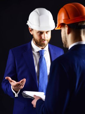 Ciddi yüzlü bina müfettişi mimarla konuşuyor..