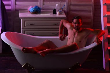 Sakallı ve kendine güveni olan bir adam banyoda çıplak.