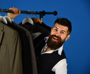 Moda seçimi konsepti. Tasarımcı takım elbiselerin arasına saklanır