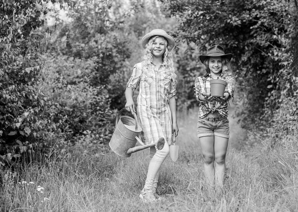 Les filles dans des chapeaux plantant des plantes. Des sœurs qui aident à la ferme. Ferme familiale. Les enfants s'amusent à la ferme. Concept d'éco-agriculture. Plantation et arrosage. Enfants rustiques arrière-plan nature. Concept d'agriculture — Photo