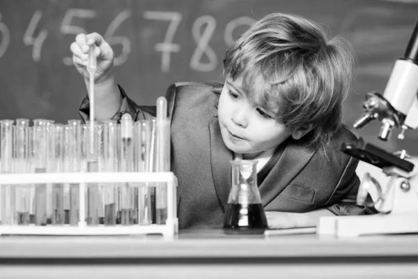 School education. Explore biological molecules. Toddler genius baby. Boy near microscope and test tubes in school classroom. Technology and science concept. Kid study biology and chemistry in school