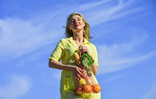 Comida saludable. bolsa con comestibles. Bolsa ecológica reutilizable para ir de compras. Mujer sosteniendo bolsa de compras de cuerda con frutas y pan en el fondo del cielo. Concepto de cero residuos. chica en vestido con bolsa de cuerda shopper —  Fotos de Stock