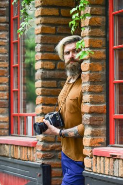 Birini arıyorum. Geçmişe dönük kamerası olan vahşi bir gezgin. Modern hayatta fotoğrafçılık. Seyahat ipuçları. Profesyonel fotoğrafçı kamera kullanır. Sakallı hippi adam fotoğraf çekiyor. Açık havada fotoğraf çekimi