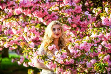 Bahar sembolü Kız bahçedeki sakuranın tadını çıkarıyor. Şefkat ve kadınlık. Kiraz ağacı. Çiçek aroması. Çiçeklerin kadınları mutlu etmesinin nedenleri. Dinlen ve tatil yap. Bahar çiçeği. Mutlu bahar günleri.