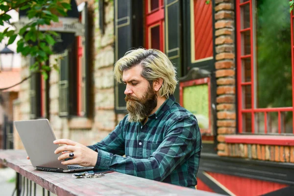 Başarılı bir girişimci. Yetişkin bir adam laptopuyla kafede oturuyor ve e-postaları kontrol ediyor. Bilgisayar üzerinde çalışan serbest çalışan bir adam. Not defteri ve telefon kullanan bir iş adamı. Ofisten kaçtı. Eğitim ve eğitim — Stok fotoğraf