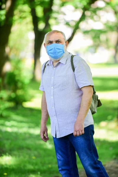 Let op de voorzorgsmaatregelen tijdens de pandemie. gezond leven. Draag een masker in het park. zorg voor je gezondheid. Bescherm jezelf tegen virussen. Een man met een beschermend masker. lopen buiten op coronavirus quarantaine. Kijk daar eens. — Stockfoto