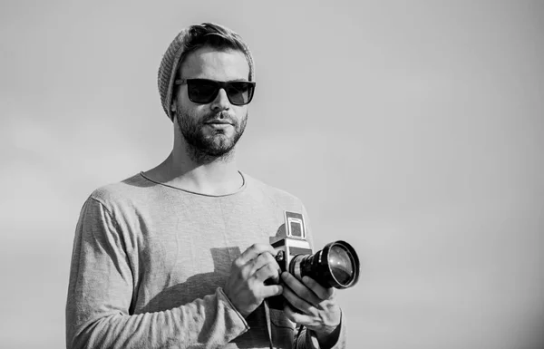 Hipsterski reporter robi zdjęcia. Koncepcja fotoreportera. Blogerka turystyczna. Profesjonalny fotograf. Przystojny fotograf, retro kamera. Ustawienia ręczne. Guy fotograf zewnątrz niebo tło — Zdjęcie stockowe