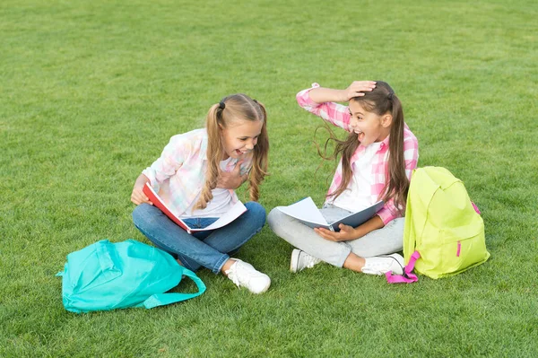 Laughing from joke. having fun on green grass. two little kids with backpack. small girl play and study on school break. happy childrens day. sisterhood and family concept. knowledge day came — Stock Photo, Image