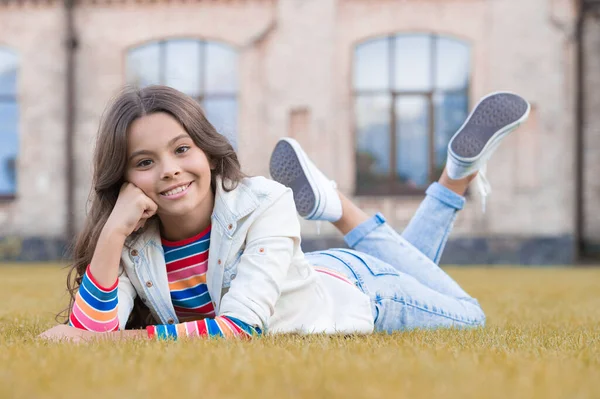 Výraz dokonalosti. Šťastná dívka odpočívá venku na trávě. Krásný vzhled malého dítěte. Vogue, podívej. Nenucený módní vzhled. Dětské oblečení. Pojď, uvolni se a užij si — Stock fotografie