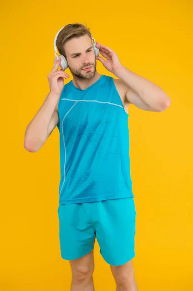 Everyone needs a tune-up. Sportsman listen to music. Sportsman training to tune. Strong sportsman wear headphones and fitness uniform. Healthy sportsman or athlete. Sport and fitness. Regular workout