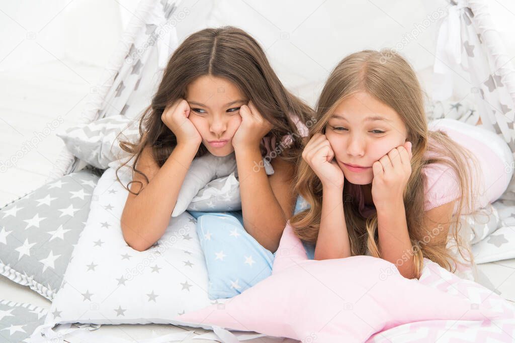 Bored kids on quarantine. Sisters best friends spend time together lay on pillows. Girls feeling sad. Girlish leisure. Sisters share gossips at home. Bored children. Boring activity. Tired and sleepy