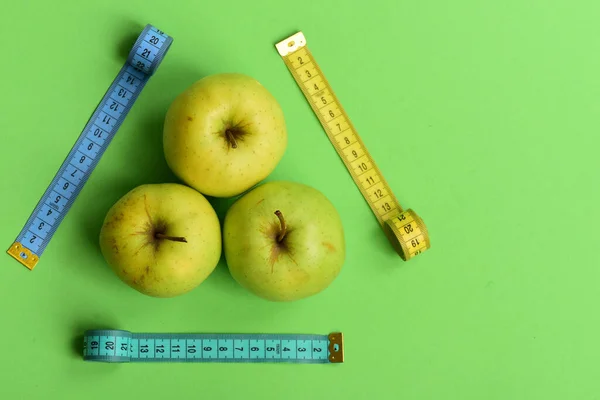 Manzanas cerca de cintas métricas trío sobre fondo verde, vista superior — Foto de Stock