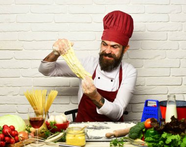 Şef para kazanıyor. Sakallı adam hamur yoğurur.