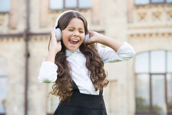 Child has music break. girl in headphones. pretty little girl wear classy uniform. back to school. modern education with new technology. kid sing at schoolyard. dream to be a singer — Stock Photo, Image