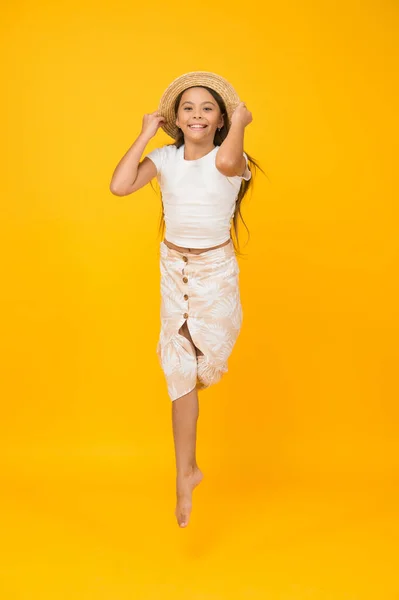 Irrequietezza saltante. piccola ragazza indossare vestito estivo. moda vacanza estiva. felice giorno dei bambini. divertirsi sulla festa in spiaggia. Ragazzo col cappello di paglia. felice salto del bambino scalzo. spensierata felicità infantile — Foto Stock