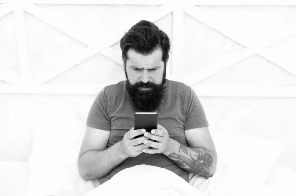 Bom dia SMS. Homem barbudo a mandar SMS para a cama. Hipster enviar sms usando smartphone. Mensagem do SMS. Serviço de mensagens curtas. Mensagens de texto por telemóvel. Estilo de vida móvel — Fotografia de Stock