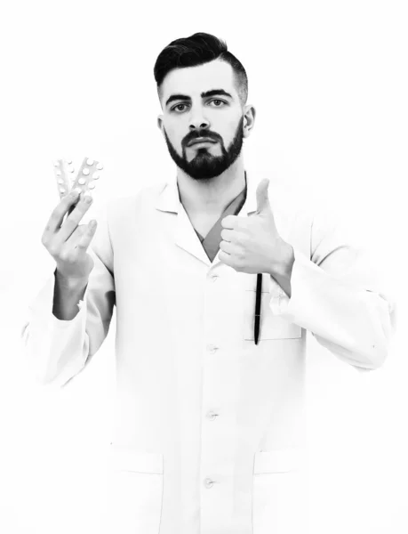 Doutor com corte de cabelo elegante e barba segura pílulas na mão — Fotografia de Stock