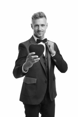 Aşkı kutluyoruz. Smokinli adam, kırmızı sevgililer günü kalbi. Romantik bir randevu için hazır. Özel bir gün. Beyaz tenli, kendine güvenen zarif bir adam. İş adamı kıyafeti. Sevgililer gününde aşk sembolü