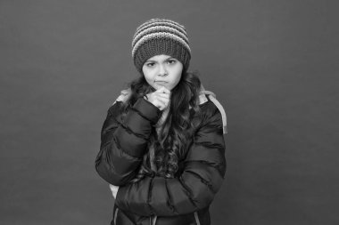 Bir şey yapmak için isteksiz. Düşünceli bir çocuk. Küçük kız kışın kırmızı arka plan giyer. Çocukluk konsepti. Duygusal kız uzun saç örgüsü şapka. Gündelik genç kızlar gibi. Duygular ve ruh hali