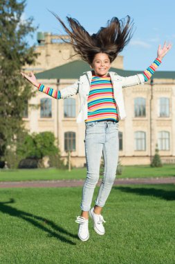 Kaygısız olmak. Enerji dolu. Çocuklar için etkinlik. Mutlu çocuk atlıyor ve kendini özgür hissediyor. çocukluk mutluluğu. Kıvırcık saçlı küçük bir kız dışarı atlıyor. Bahar bayramı kutlaması. Çocuk hareket halinde.