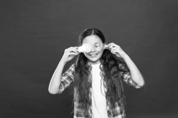 Bombilla de niña pequeña. energía y electricidad. creando una gran idea. Niña pensante. niño pequeño mantenga la bombilla idea de luz. concepto de educación. pequeño escuela niño rojo fondo — Foto de Stock