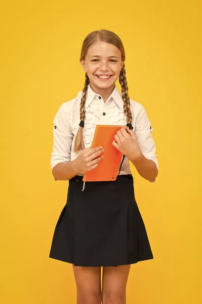 Υπέροχο βιβλίο, υπέροχες πληροφορίες. Ευτυχισμένο μικρό κορίτσι κρατώντας το βιβλίο με πληροφορίες για το κίτρινο φόντο. Μικρό παιδί που παίρνει πληροφορίες από το βιβλίο της βιβλιοθήκης. Πληροφορίες για το σχολείο — Φωτογραφία Αρχείου