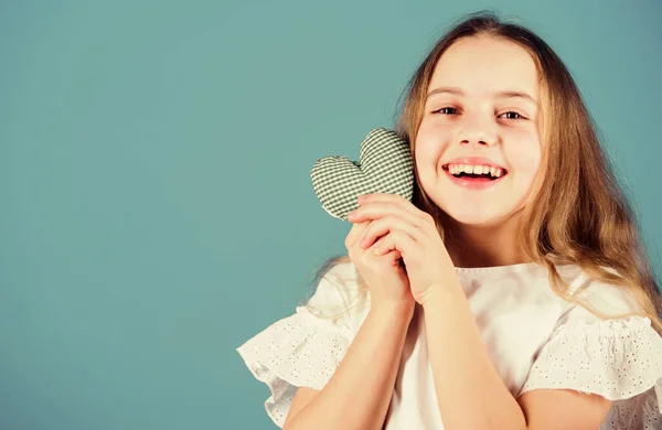 Her sweet smile warms the hearts. Happy child with adorable smile holding small heart. Little girl with happy smile on beautiful face. Smiling kid looking happy on Valentines day, copy space