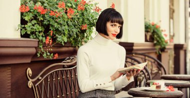 İş kadını kahve molasında kitap okurdu. Mükemmel hafta sonu için kahve ve iyi bir kitap. Kişisel gelişim konsepti. Kadınlar kafeterya terası okumaktan zevk alır. Modern kadın edebiyatı