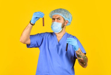 İnsandan insana iletim. Sürekli yeni virüsler tespit ediliyor. Virüs salgınının başlangıcı. Erkek doktor üniforması, sarı arka plan. Bir çeşit virüs. Coronavirus konsepti. Virüsün mutasyona uğramasını bekle