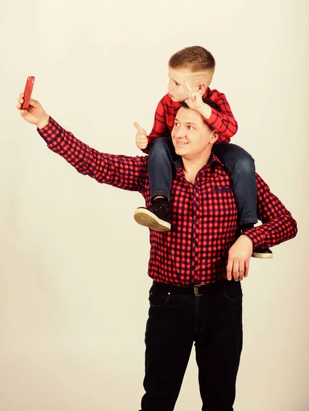 Father example of noble human. Father little son red shirts family look outfit. Taking selfie with son. Child riding on dads shoulders. Happiness being father of boy. Having fun. Fathers day