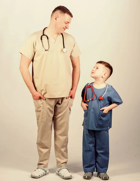 Want to be doctor as dad. Cute kid play doctor game. Family doctor. Pediatrician concept. Medicine and health care. Father doctor with stethoscope and little son physician uniform. Future profession — ストック写真