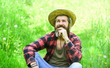 Hasır şapkalı rahat bir çiftçi. Yetişkin bahçıvan yeşil çimlerde rahatlar. Bahar doğasının tadını çıkar. Yaz sezonu mükemmeldi. Vahşi çiftlik hippileri kareli gömlek giyer. Çiftçilik ve tarım. Yeşil yaşam