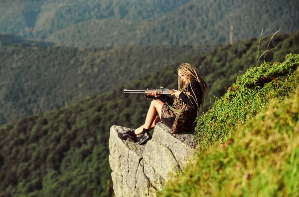 Hunter hegyek táj háttér. Szexi harcos. Nő vonzó hosszú haj csinos arc fogja puska vadászat. Amazon lány ül a sziklán előkészíti a fegyvert a vadászatra. Célzás koncepció. Vadászati idény — Stock Fotó