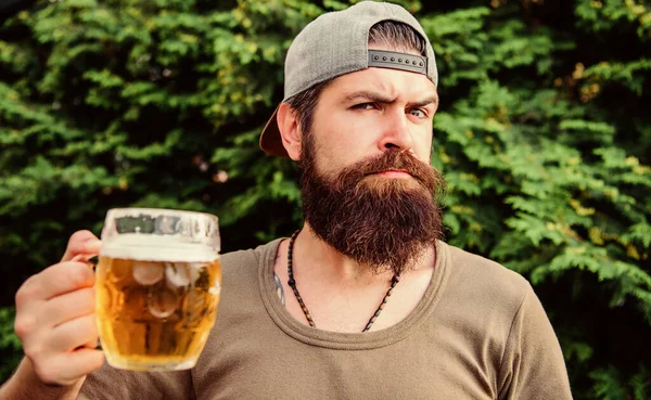 Ontsnappen aan de zomerhitte. Brute hipster die verfrissend bier drinkt op zomerdag. Een man met baard en biermok op de zomerse natuur. Drinker geniet van de zomer — Stockfoto