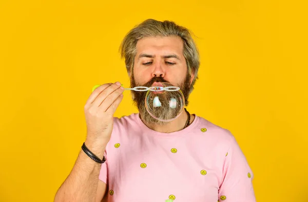 Atmosfera de festa ou férias. sensação infantil e infantil. verdadeira felicidade. homem maduro soprando bolhas de sabão. homem com soprador de bolhas. hipster feliz em humor brincalhão. Cair na infância. criatividade — Fotografia de Stock