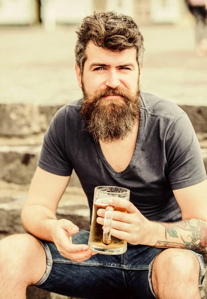 Kawiarnia letni taras. Lekkie piwa lub ciemne Stout pić je wszystkie. Człowiek z brodą i wąsy trzymać piwo ze szkła na zewnątrz. Facet odpoczywać z piwem z zimnego zanurzenia. Hipster zrelaksowany picie piwa na zewnątrz — Zdjęcie stockowe