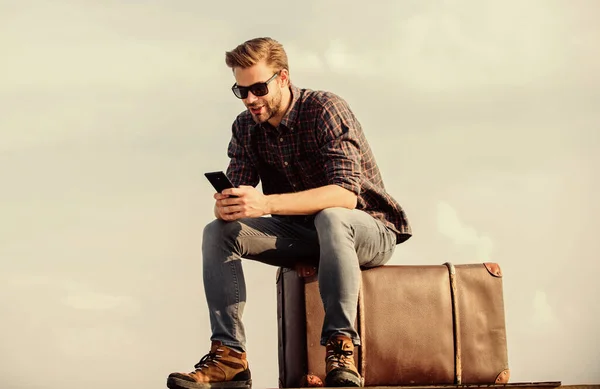 Schöner Reisender. Mann im Freien mit Vintage-Koffer. Transporteinrichtungen. Taxi rufen. Reisebüro. Reisen mit Gepäck. Reiseblogger. Mann sitzt vor Reise auf Koffer Gepäckkonzept — Stockfoto